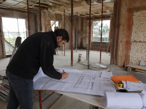 Contrôle des plans au cœur du chantier de rénovation, entre les étais et les murs mis à nu